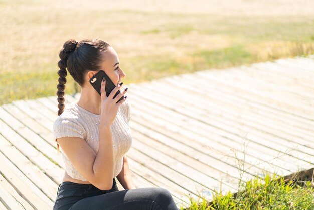 屋外で誰かと携帯電話で会話を続ける若いモロッコの女の子