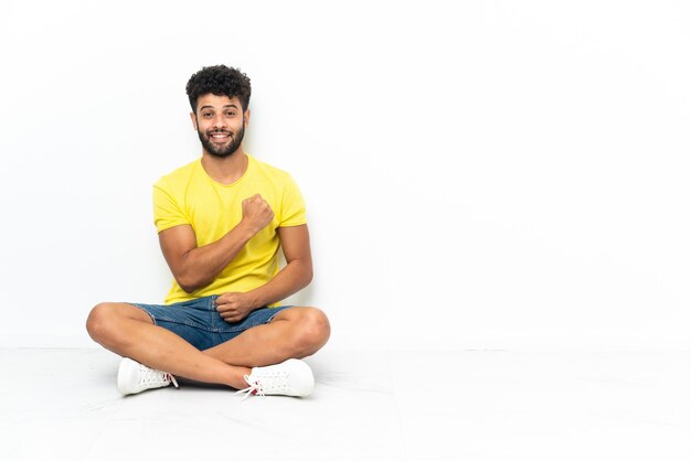 Young Moroccan handsome man sitting on the floor isolated