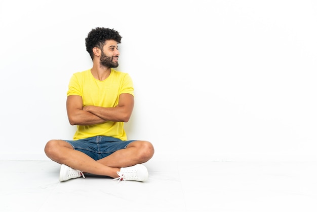 Young Moroccan handsome man sitting on the floor isolated