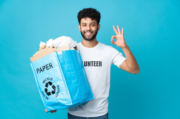 Young Moroccan man holding a recycling bag full of paper to recycle isolated