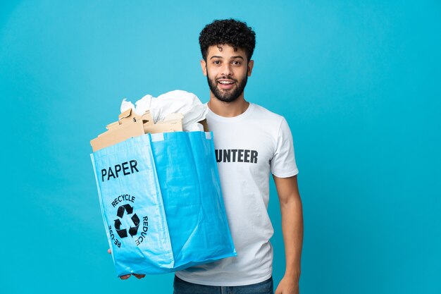 Young Moroccan man holding a recycling bag full of paper to recycle isolated