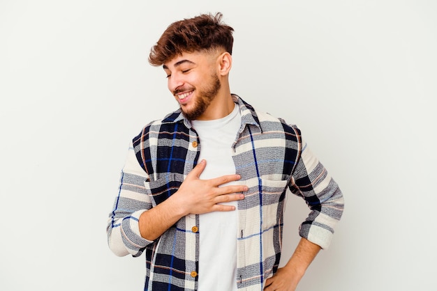 Young Moroccan man isolated on white laughing keeping hands on heart, concept of happiness.