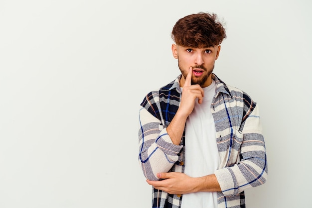 Young Moroccan man isolated on white looking sideways with doubtful and skeptical expression.