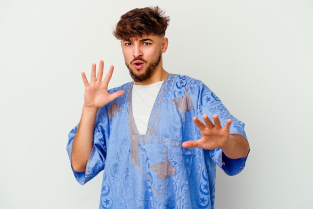 Young Moroccan man isolated on white rejecting someone showing a gesture of disgust.