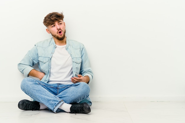 Young Moroccan man sitting on the floor   suffering a back pain.