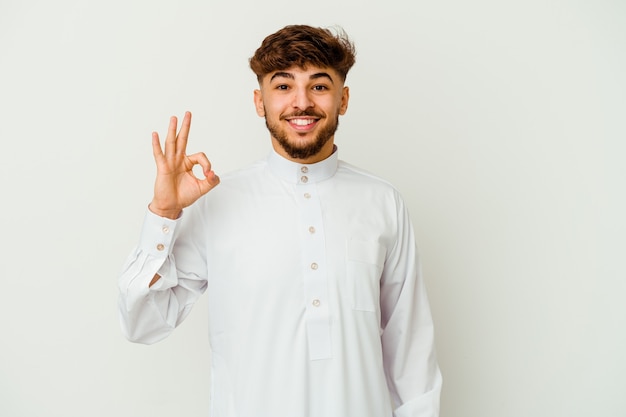 Young Moroccan man wearing a typical arab clothes  cheerful and confident showing ok gesture.