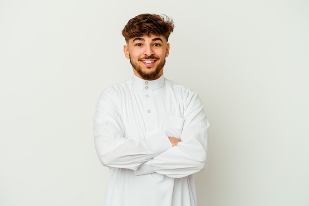 Young Moroccan man wearing a typical arab clothes isolated on white wall who feels confident, crossing arms with determination.