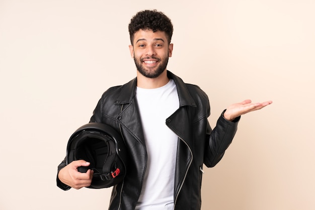 Young Moroccan man with a motorcycle helmet isolated on beige with shocked facial expression