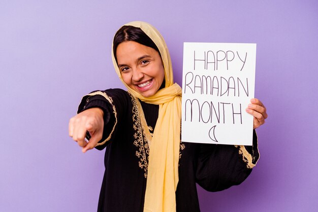 Young Moroccan woman holding a happy ramadan placard isolated on purple wall