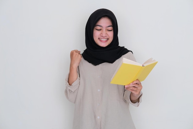 Young moslem girl clenching fist showing excitement when reading a book