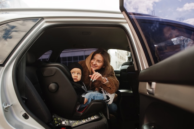 車の中で若い母と子。椅子のベビーシート。安全運転のコンセプト。