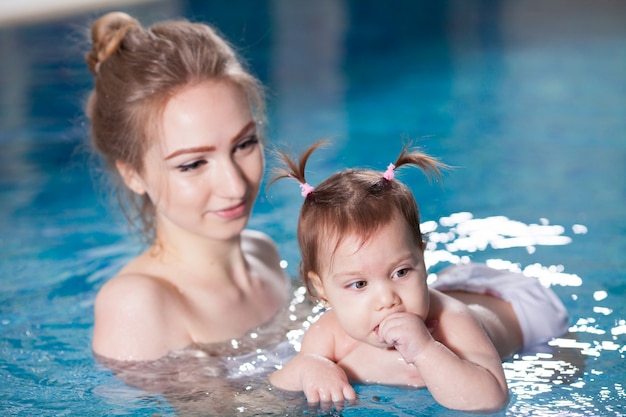 Young mother bathes the baby in the pool.