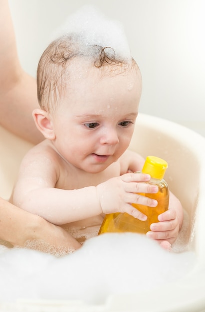 Young mother bathing her baby boy in bath