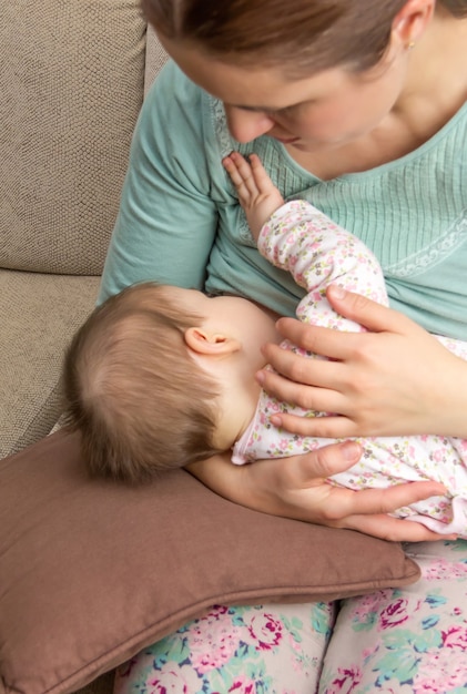 自宅で赤ちゃんに授乳している若い母親