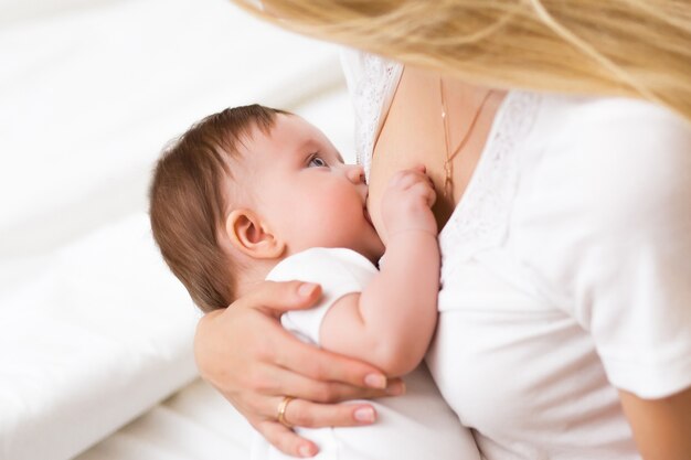 Una giovane madre che allatta al seno la sua piccola bambina tenendola tra le braccia