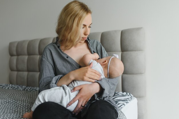 Photo young mother breastfeeding her newborn baby boy at home