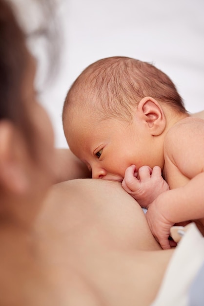 自宅で生まれたばかりの赤ちゃんを母乳で育てる若い母親