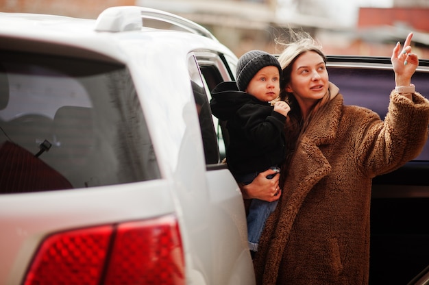 Young mother and child stand near they suv car. Safety driving concept.