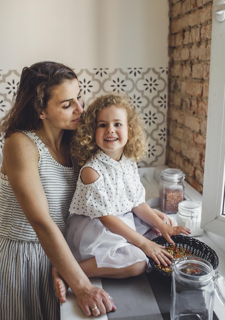 A young mother cooks pasta in the kitchen with her little daughter. joint cooking