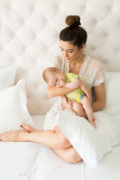 Young mother and cute baby girl on the bed