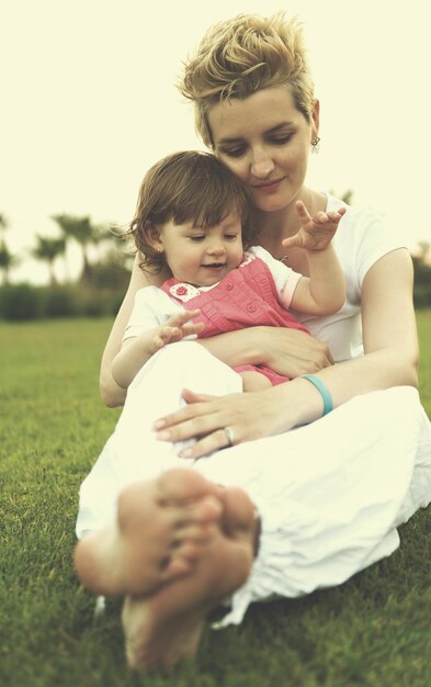 Young Mother and cute little daughter enjoying free time playing outside at backyard on the grass, happy family in nature concept