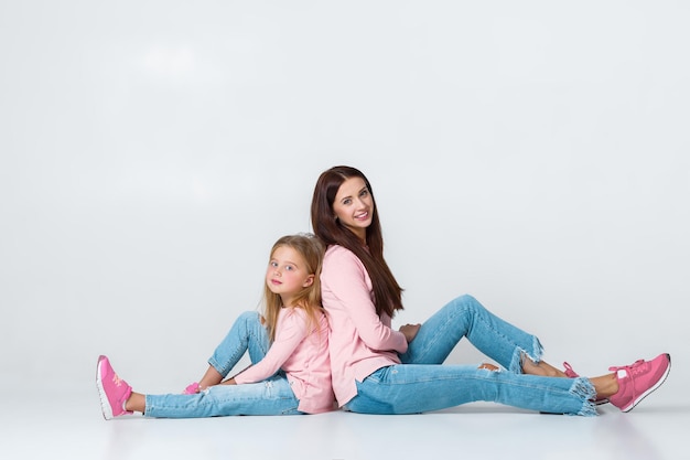 Young mother and daughter having fun together on gray background