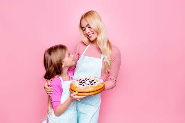 Young mother and daughter holding cake