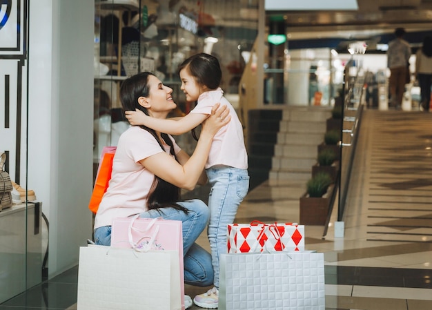 Foto giovane madre e figlia che tengono i sacchetti della spesa che comperano nel centro commerciale acquisto della famiglia