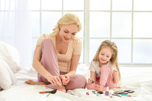 Young mother and daughter morning on bed indoors