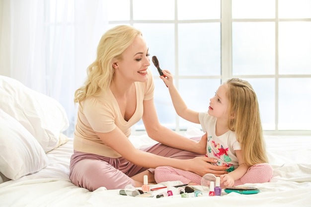 Young mother and daughter morning on bed indoors