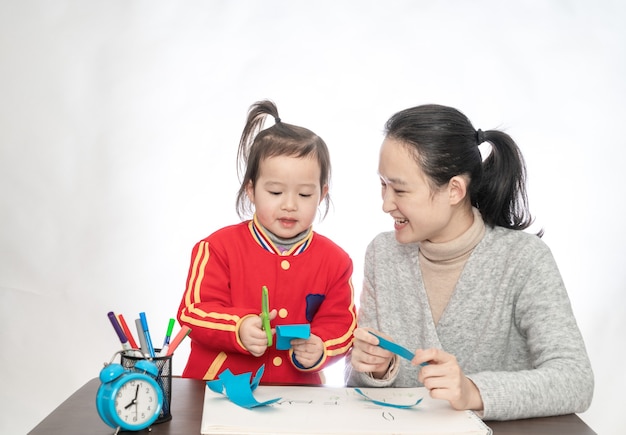 Young mother and daughter playing paper cut