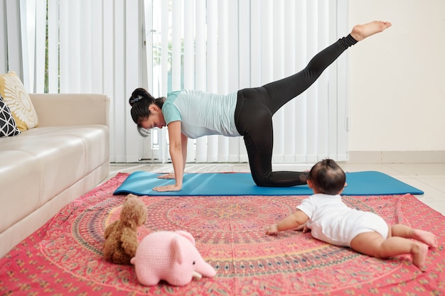 Giovane madre che si esercita sulla stuoia di yoga