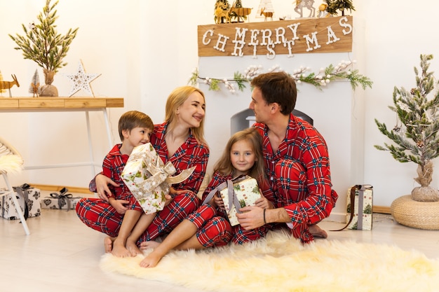 Young mother and father and two little children sitting by a fireplace