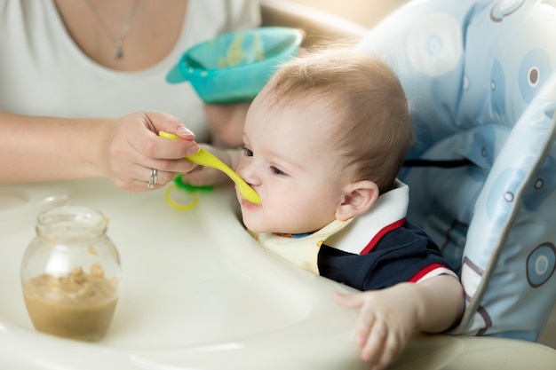 Young mother feeding her baby in highchair