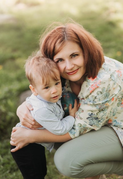 Young mother gently hugs her son Todler in the park on a sunny day