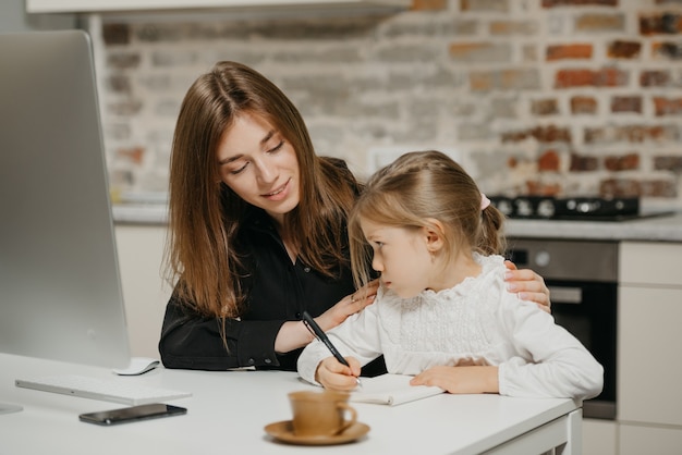 Photo young mother helping her daughter with homework