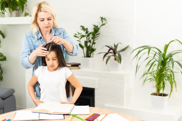 Young mother helping her little child get ready for school at home.