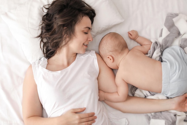 Young mother and her baby lying on bed at home