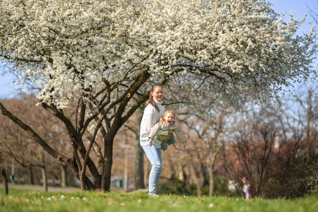 Young mother and her cute daughter having a fun in spring time park in prague europe