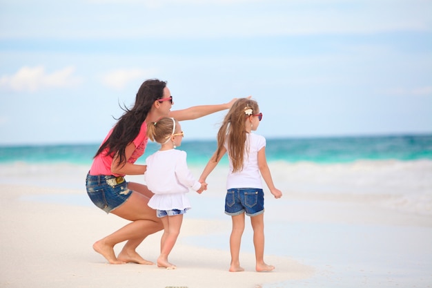 Young mother and her cute daughters enjoy summer vacation at tropical beach