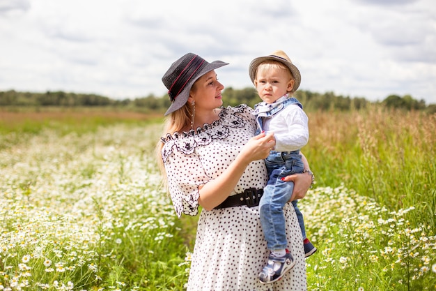 Young mother and her cute little son walking in a field