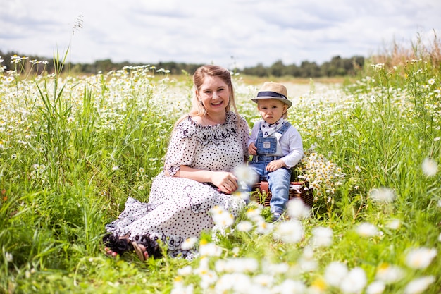 Young mother and her cute little son walking in a field