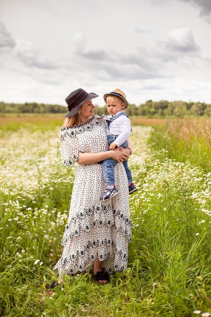 Young mother and her cute little son walking in a field