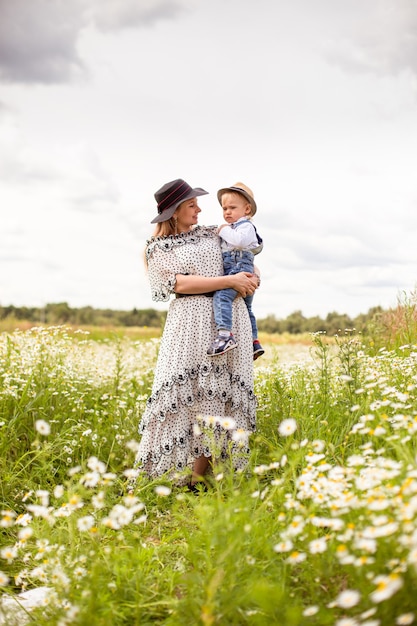 Young mother and her cute little son walking in a field