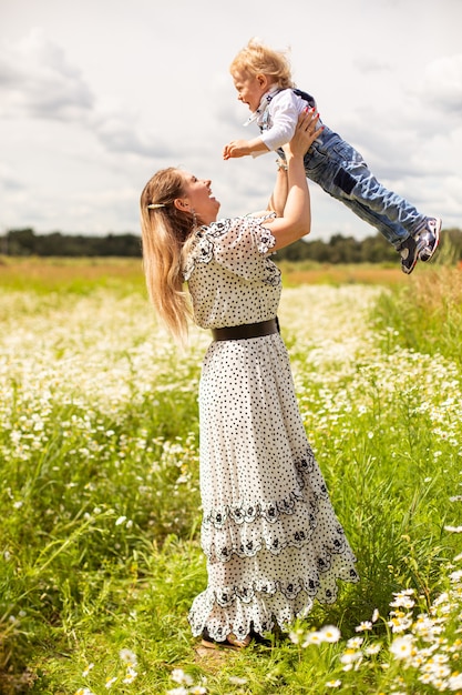 Young mother and her cute little son walking in a field