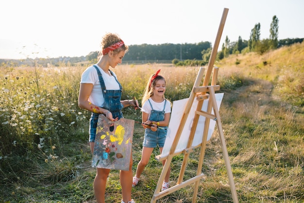 Photo young mother and her daughter have fun, . smiling mother with beautiful daughter draws nature