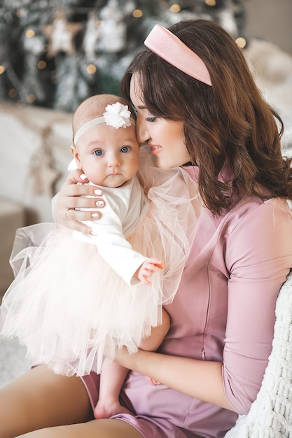 Photo young mother and her little baby daughter with christmas tree