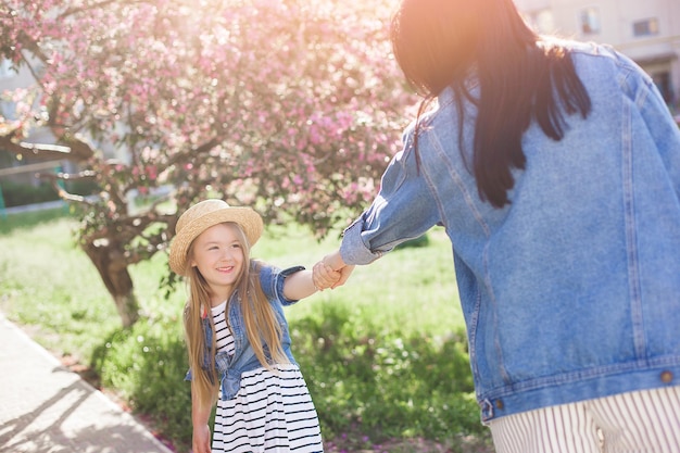 若い母親と彼女の小さなかわいい娘は、屋外で楽しんでいます。一緒に家族の女の子。