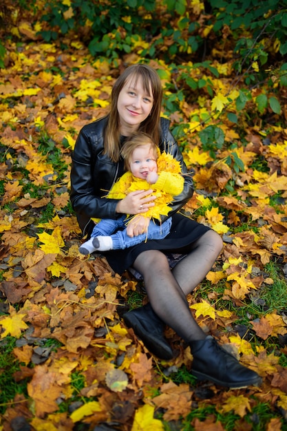 Giovane madre e la sua ragazza del bambino nei campi di autunno