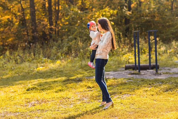 Young mother and her toddler girl have fun in autumn.